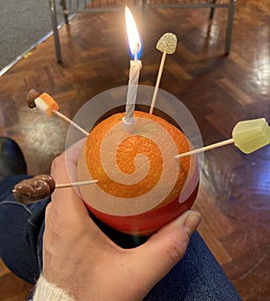 Christingle Orange, wrapped in red tape, decorated with dried fruit or sweets, with a candle on the top. photo