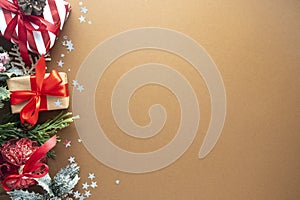 Christmas abstract background. Craft gift boxes with red bow and winter decorations on brown background, top view. Copy space