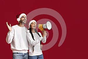 Christmas Ad. Middle Eastern Couple In Santa Hats Making Announcement With Megaphone