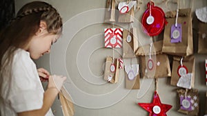 Christmas advent calendar for kids. child takes and opens handmade gift.