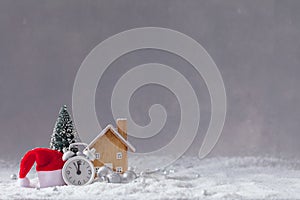 Christmas alarm clock, Santa Claus hat, small wooden toy cottage and fir-tree with balls, postcard concept