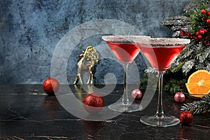 Christmas alcoholic cocktail with red martini, lemonade, champagne in glasses on festive background with fir branches and