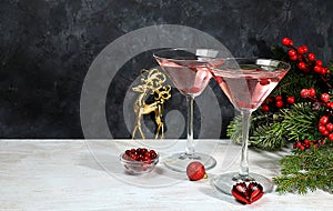 Christmas alcoholic cocktail with red martini, lemonade, champagne in glasses on festive background with fir branches and