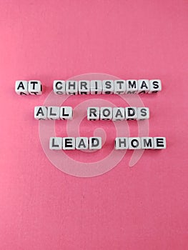 At Christmas all roads lead home heart warming Christmas saying on a pink background