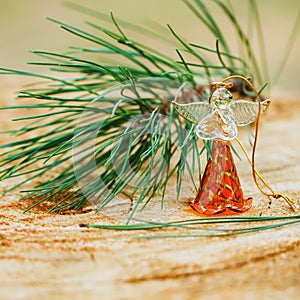 Christmas angel made fromfrom glass with a branch of natural pine on wood background, holiday decorations