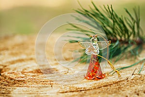 Christmas angel made fromfrom glass with a branch of natural pine on wood background, holiday decorations and backcloths
