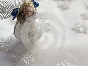Christmas angel toy across white background with snowflakes.