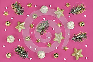Christmas arrangement with pine branches, golden star ornaments and tree baubles and white snow balls on pink background