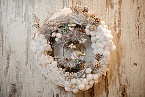 Christmas artificial wreath with little white cotton balls, cones and toy birds