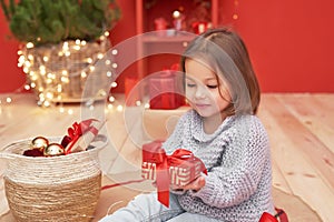 Christmas baby. Child girl with gifts on background of Christmas tree. Xmas greeting card. Merry christmas background. Happy New