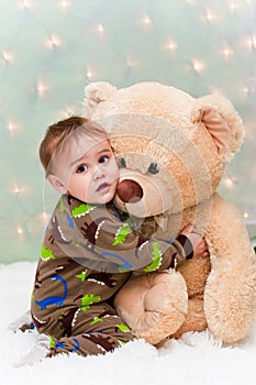 Christmas baby in pajamas holding teddy bear