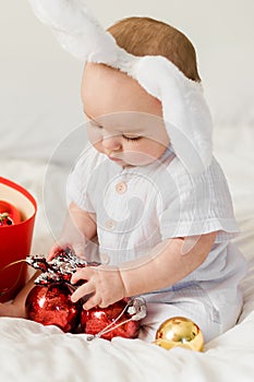 Christmas Baby in Santa Hat Child playing with baubles close-up. Present Gift Box over Holiday Lights background and