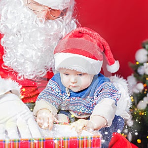 Christmas baby and Santa opening a present or gift box