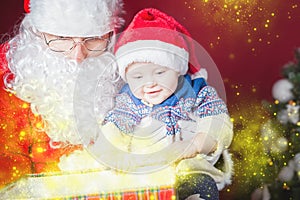 Christmas baby and Santa opening a present or gift box