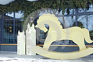 Christmas backdrop with wooden toys and decorated cafe window. Wooden horse and wooden houses in front of the cafe