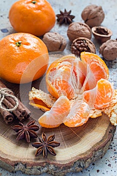 Christmas background. Aromatic winter spices, walnuts and mandarins laying on wooden log, vertical