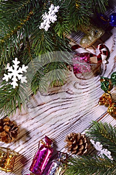 Christmas background. Artificial spruce branches with cones and New Year`s toys on a wooden surface.