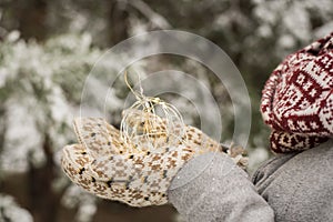 Christmas background with ball of Christmas light  in hands clothed with woolen handmade ethnic mittens