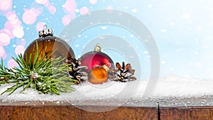 Christmas background banner long - Red baubles, pine branches and pine cones on snowy wooden rustic table with blue sky with