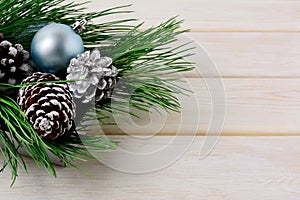 Christmas background with blue ornaments, silver and snowy pinecones