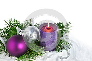 Christmas background with candle and decorations. Purple and silver Christmas balls over fir tree branches