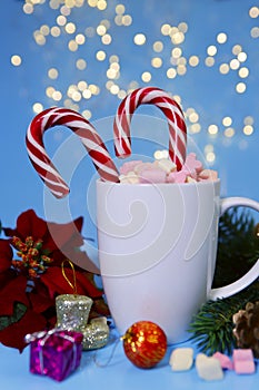 Christmas background.Candy cane inserted into a white cup with marshmallows.