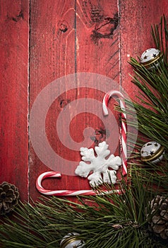 Christmas background with candy pine branches and pine cone, decorations on red wooden rustic background top view