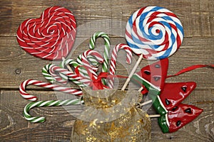 Christmas background with candy set of lollipops, a red heart, a candy cane, a watermelon and a ball a wooden background. Concept