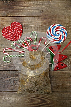 Christmas background with candy set of lollipops, a red heart, a candy cane, a watermelon and a ball a wooden background. Concept