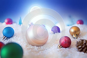 Christmas background with Christmas balls on snow over fir-tree, night sky and moon. Shallow depth of field