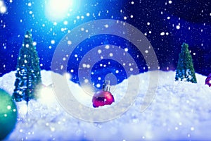 Christmas background with Christmas balls on snow over fir-tree, night sky and moon. Shallow depth of field. Christmas background