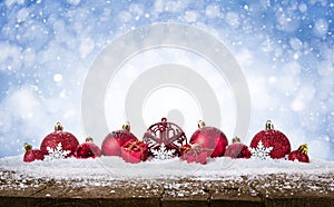 Christmas Background - Decorated Red Balls On Snow with snowflakesand stars on wooden desk