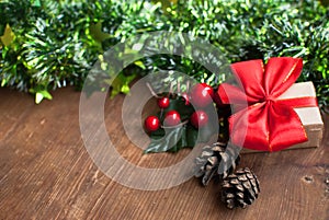 Christmas background with decorative composition of green tinsel, dried oranges, red berres, pine cone, gift with red bow and