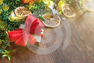 Christmas background with decorative composition of green tinsel, dried oranges, red berres, pine cone, gift with red bow and