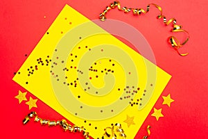 Christmas background. Decorative ornaments in the form of stars and gold ribbons lie on a red and yellow background