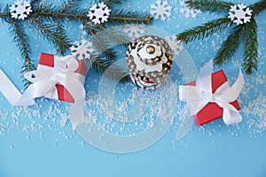 Christmas background with fir branches, bell and snowflakes and gift red box with white ribbon on the blue background. Christmas.