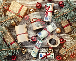 Christmas background, fir branches, gifts, baubles, money of different values. Top view