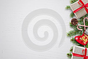 Christmas background with fir branches, gifts, sock and pinecones on right side. Free space for text on left side. White wooden ba