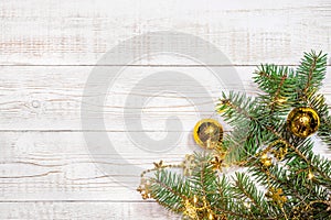 Christmas background - fir branches with golden decorations and light garland on a white wood table. Flat layout, top view