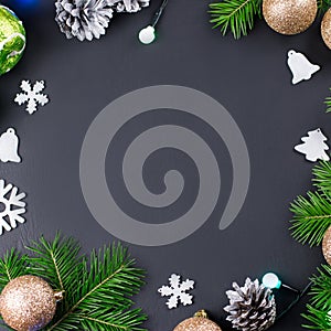 Christmas background with fir branches, lights, golden and silver decorations on black wood