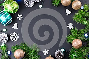 Christmas background with fir branches, lights, golden and silver decorations on black wood