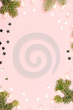 Christmas background with fir branches, lights, pink decorations on pink