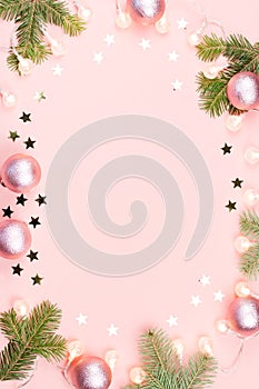 Christmas background with fir branches, lights, pink decorations on pink