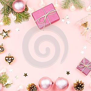 Christmas background with fir branches, lights, pink decorations on pink