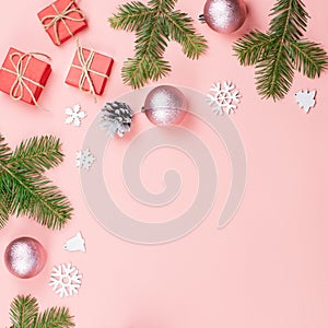 Christmas background with fir branches, lights, red giftboxes, pink decorations, hot drink with marshmallows on pink