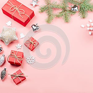 Christmas background with fir branches, lights, red giftboxes, pink decorations, hot drink with marshmallows on pink