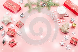 Christmas background with fir branches, lights, red giftboxes, pink decorations, hot drink with marshmallows on pink