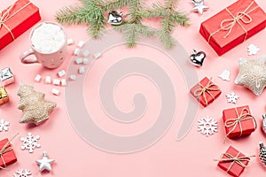 Christmas background with fir branches, lights, red giftboxes, pink decorations, hot drink with snow falling