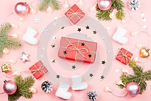 Christmas background with fir branches, lights, red presents, pink decorations on pink