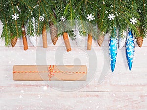 Christmas background with fir branches, snowflakes, toys, cinnamon, cone, present on brown wooden background